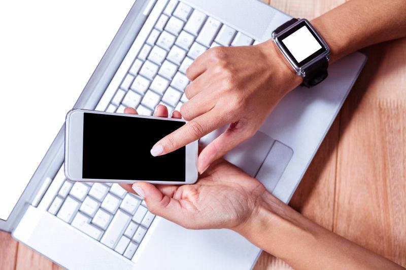 白色笔记本上男人在使用智能手机