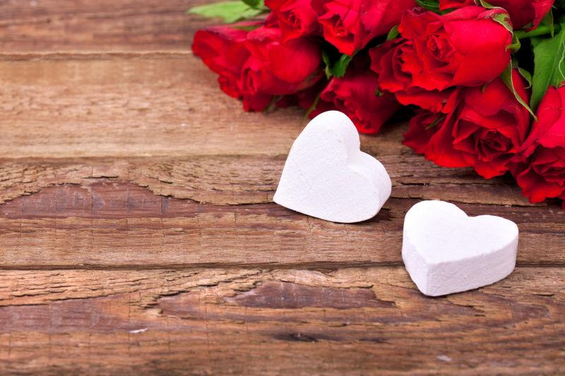 木制背景下的爱心和红玫瑰