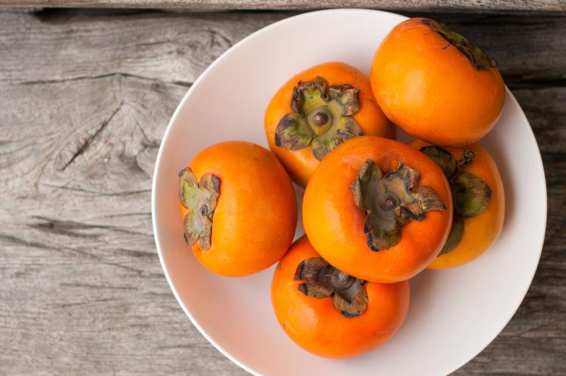 目中上白色盘子中的新鲜柿子