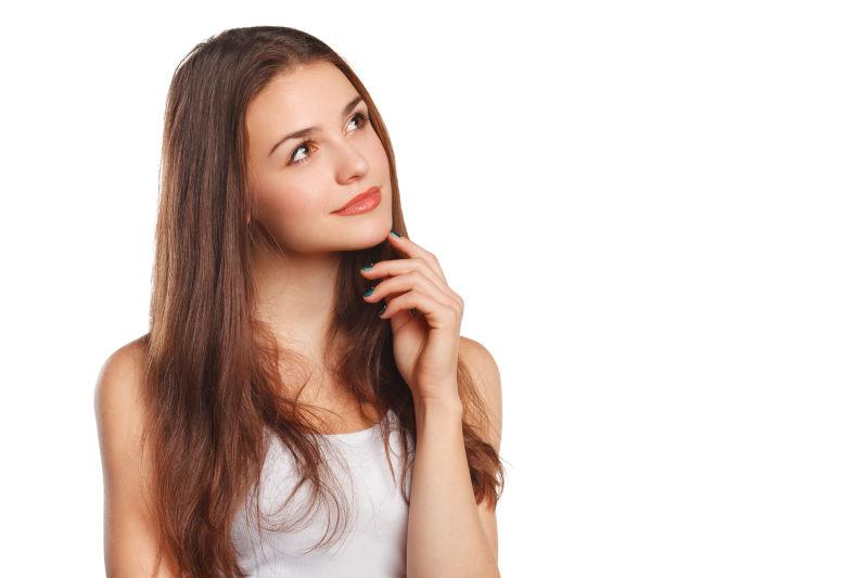 白色的背景中的年轻美貌的女人边看边思考