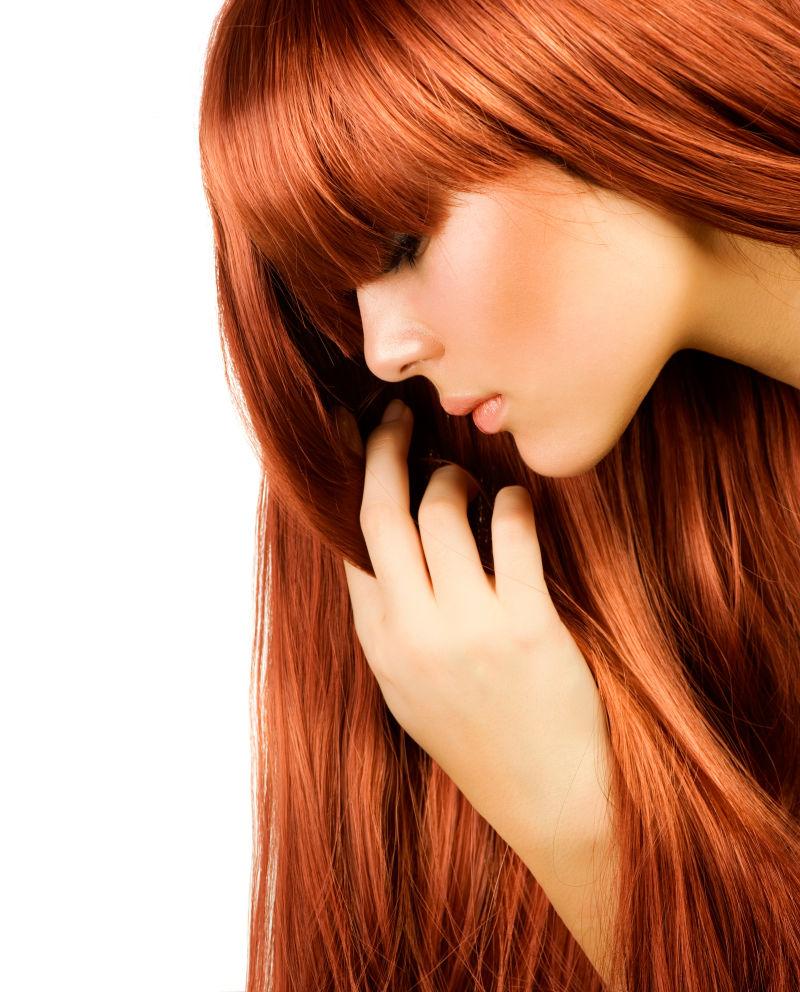 在白色背景下漂亮的女孩拥有健康的红色长发