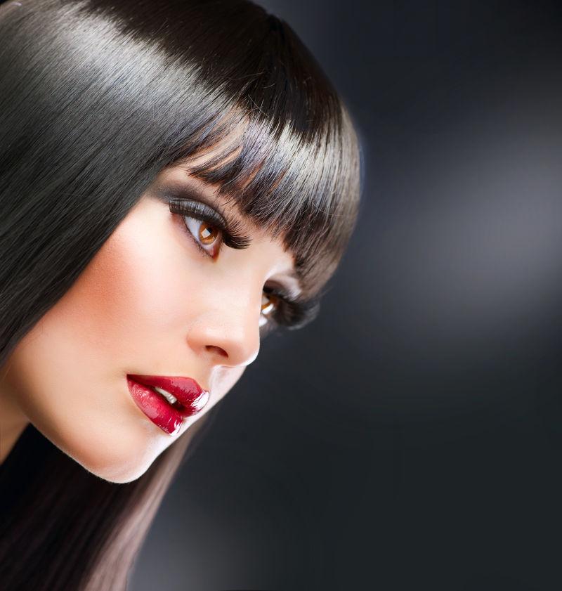 在黑色背景下拥有时尚的黑色长发的美女