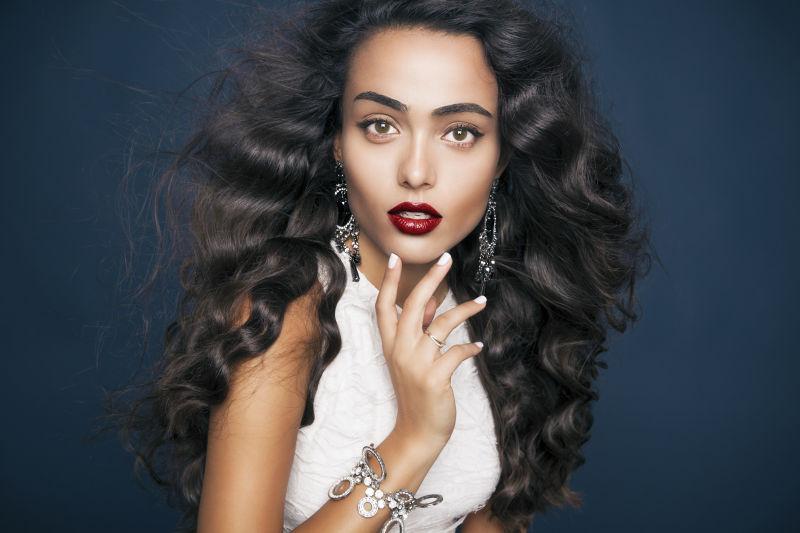 在黑色背景下拥有时尚的波浪式发型的迷人的女人