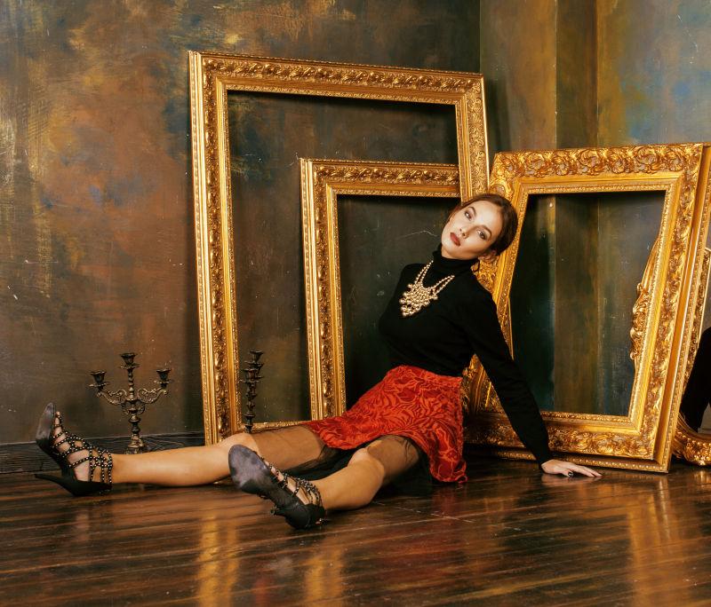 美丽富丽堂皇的女人在奢华的室内靠近空空的框架