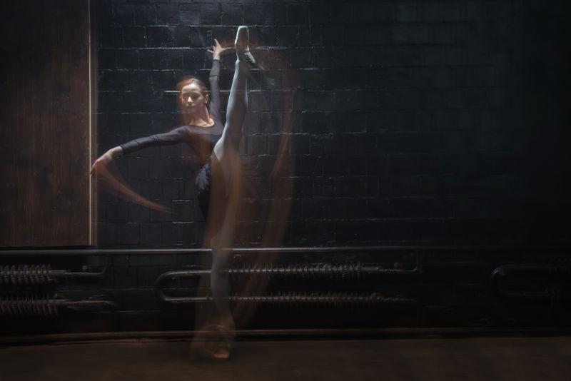 年轻的芭蕾舞蹈演员在黑暗的背景下展示