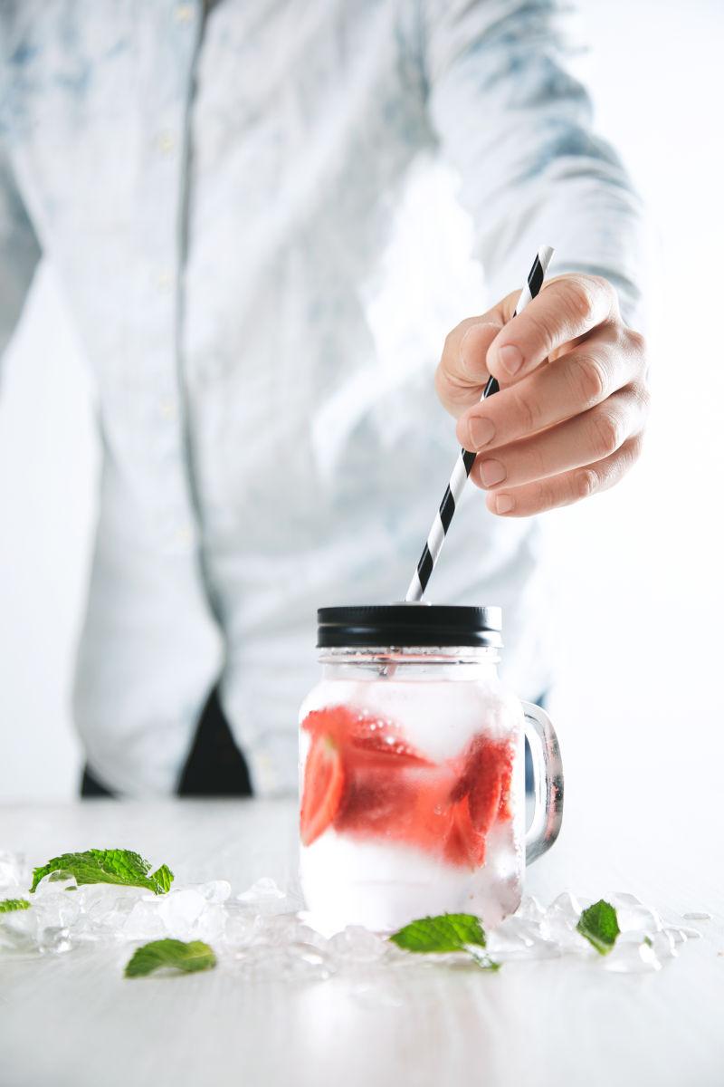 酒吧服务员把带条纹的吸管放在饮料罐子里
