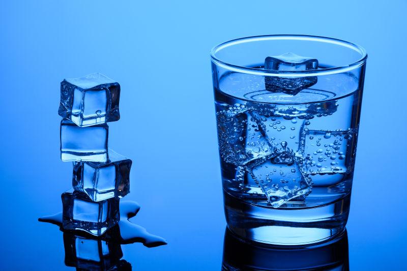 蓝色背景上的冰块和一杯冰饮料