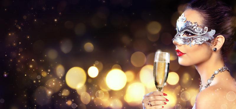 戴面具的性感美女手拿香槟