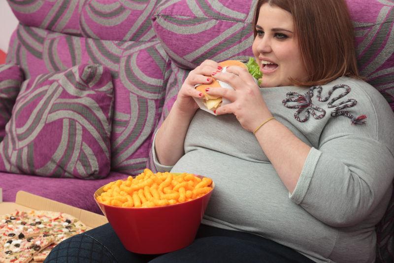 坐在沙发上吃快餐的胖女人
