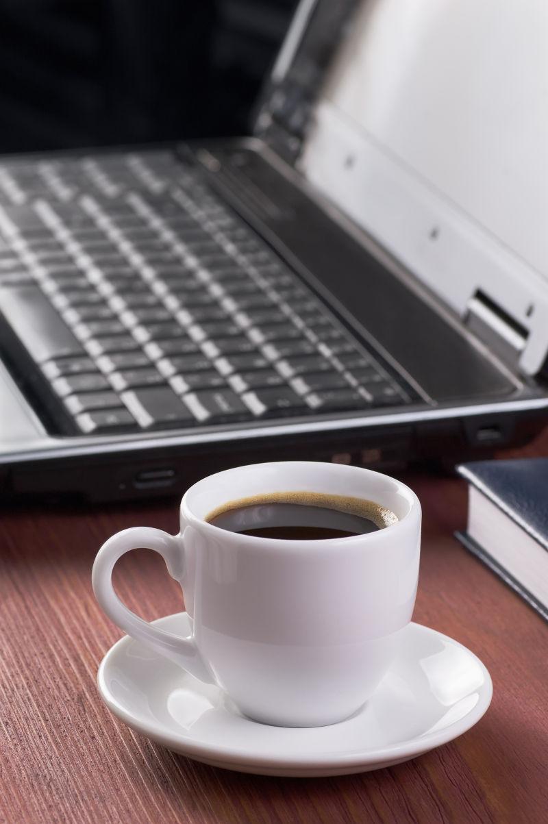木纹理桌上的笔记本电脑旁边的一杯咖啡