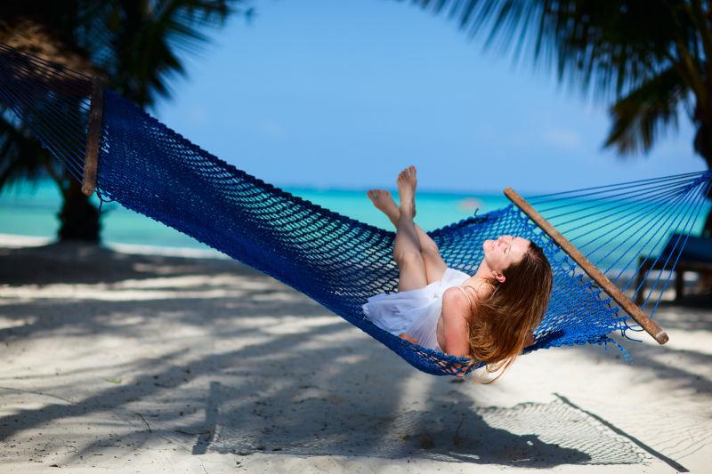 在热带海滩吊床上放松的年轻美女