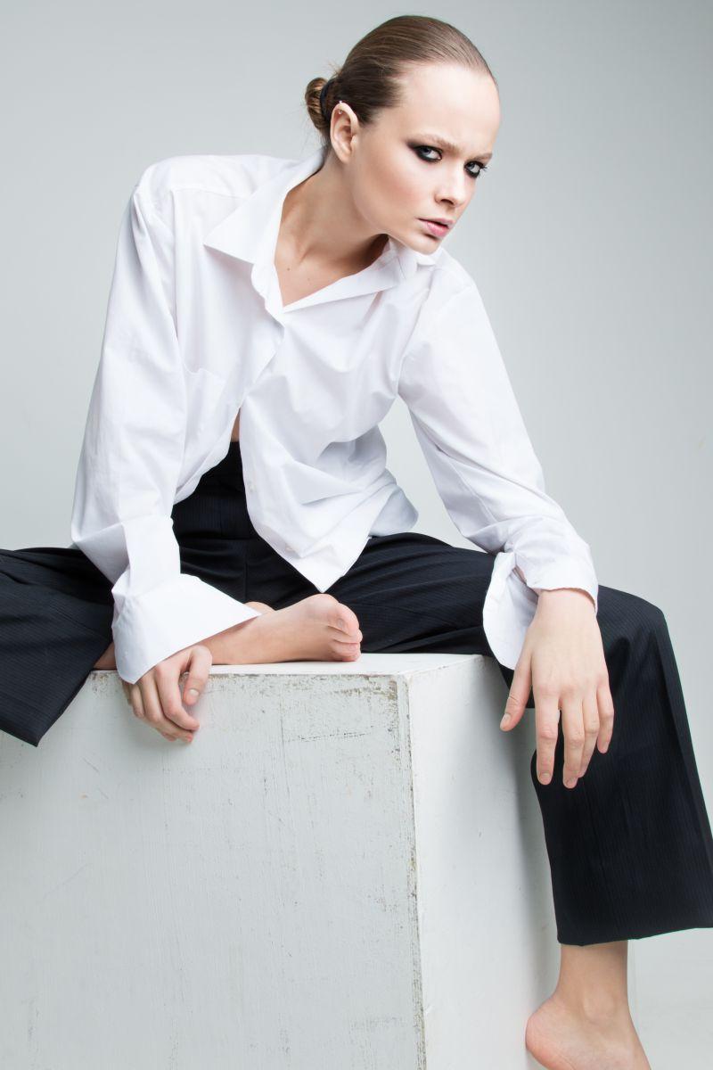 灰色背景上坐在白色台子上的时尚女人