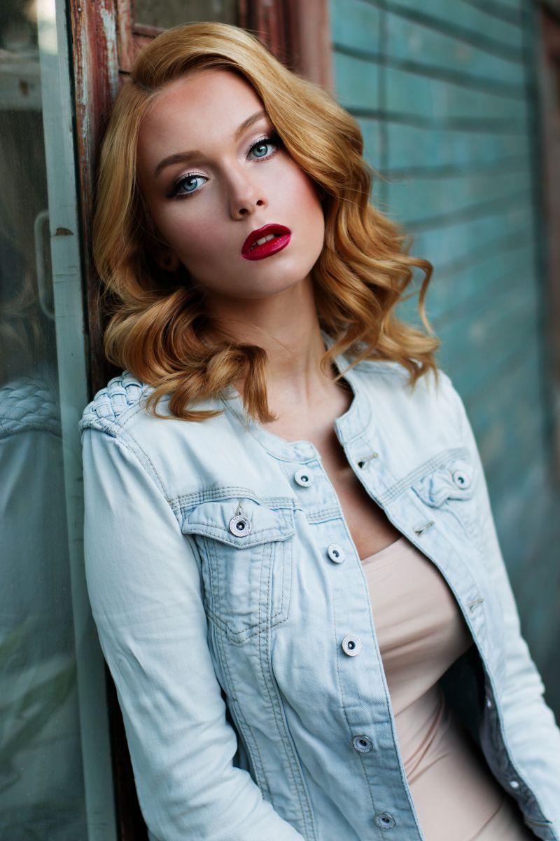 穿着牛仔外套靠在门上的金发美女