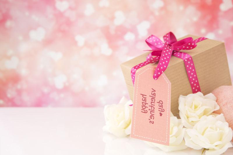 白色桌面上美丽的白玫瑰和情人节礼物