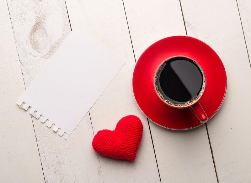桌子上的红色咖啡杯和空白卡片还有个红色爱心