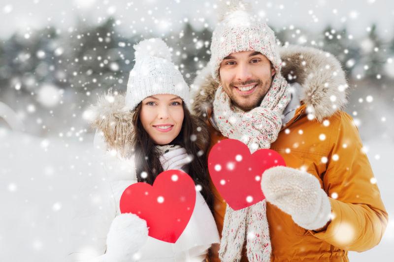 下雪天一对情侣拿着一对红色心