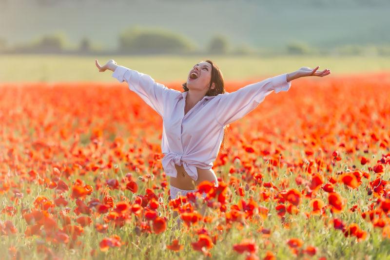 张开双臂站在罂粟田里的女孩
