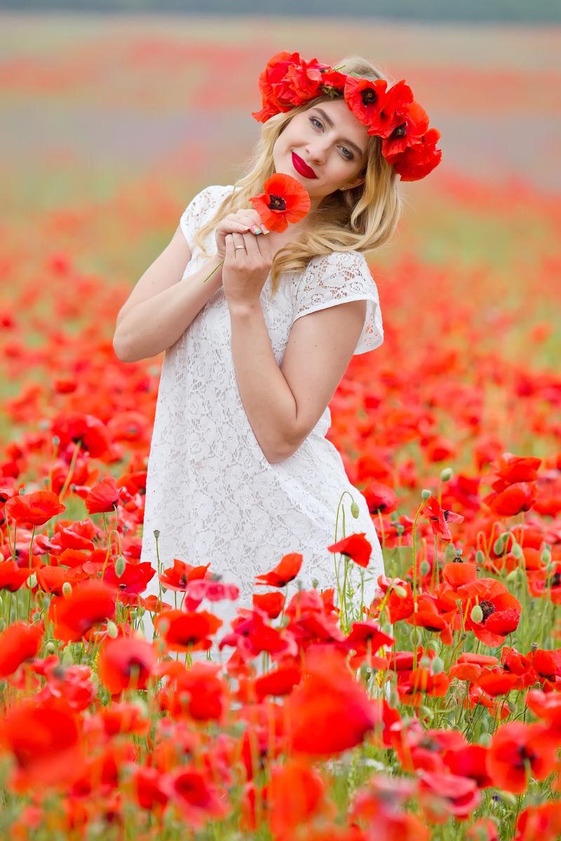 站在花丛里手拿红色花朵的美女