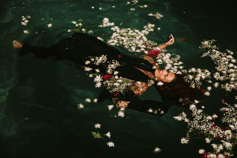 躺着有花瓣的游泳池的美女