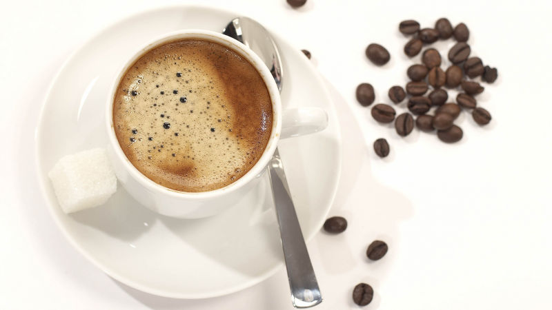 一杯加糖的咖啡与旁边的咖啡豆