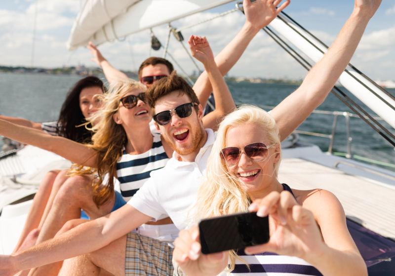 微笑的朋友坐在游艇甲板上自拍