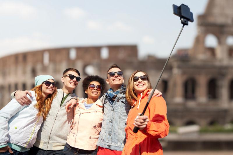 罗马背景下的拿着智能手机自拍的朋友们