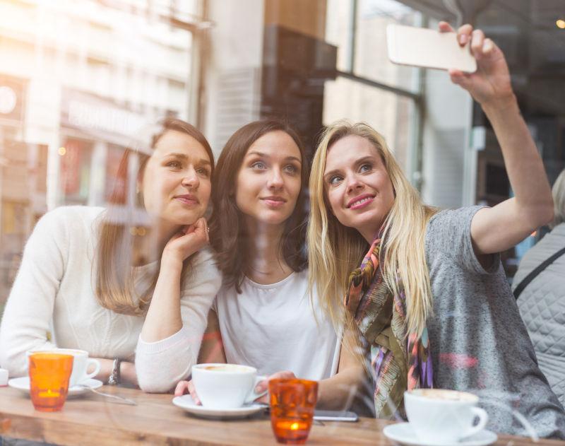 自拍的快乐的女人在哥本哈根的咖啡馆里