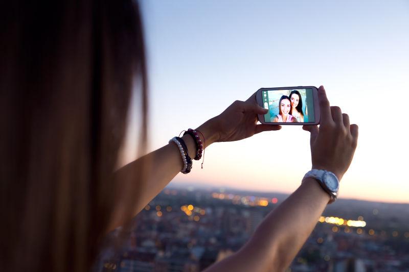 美丽的女孩在夕阳下的屋顶上自拍