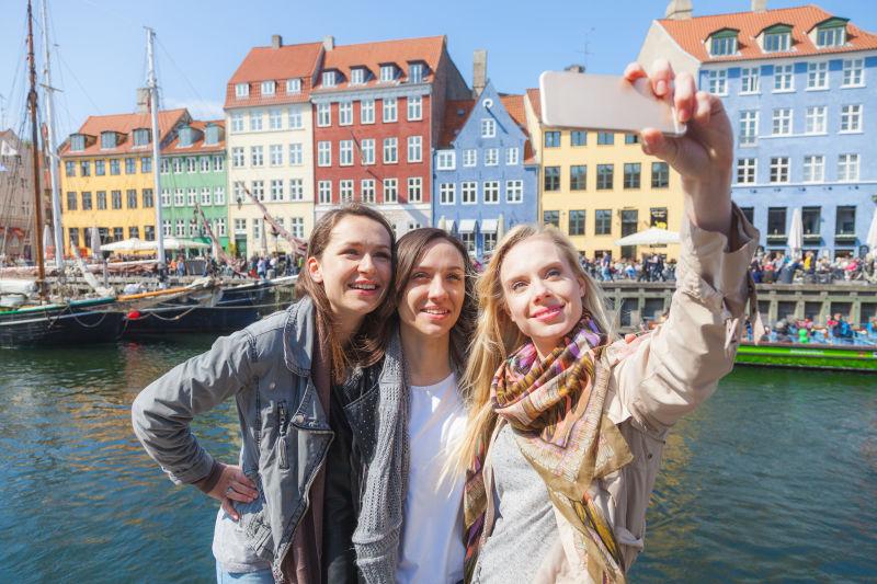 在尼哈文区有着色彩鲜艳的房子的背景下自拍的女性朋友