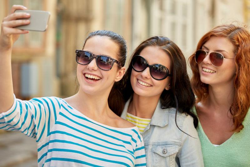 戴太阳镜微笑自拍的年轻女性