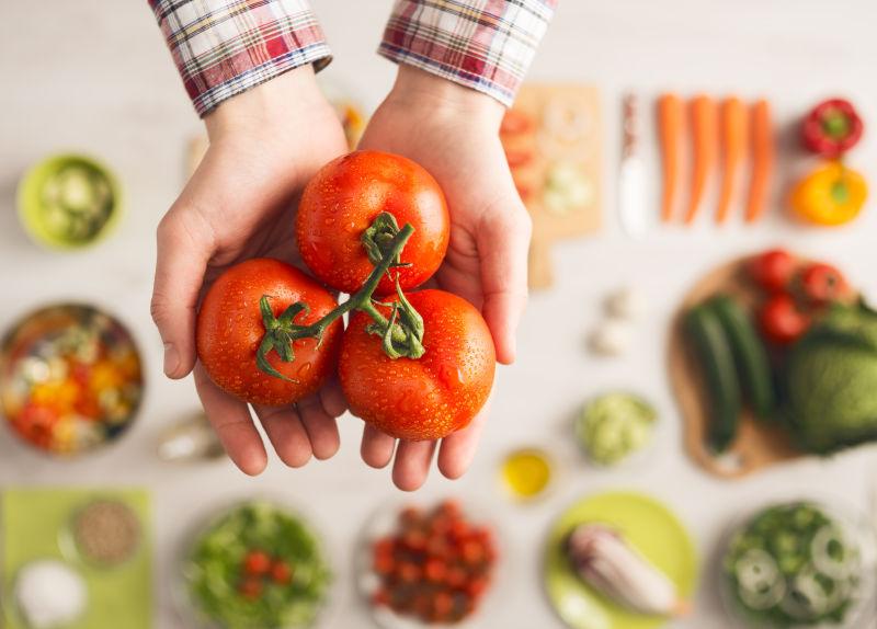 男人手里三个新鲜的西红柿