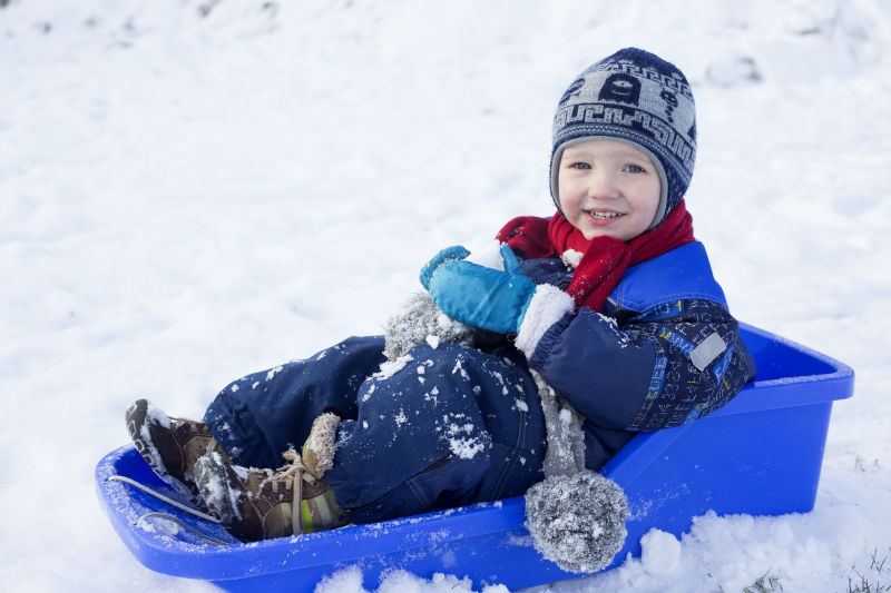 孩子坐在雪橇车里滑雪