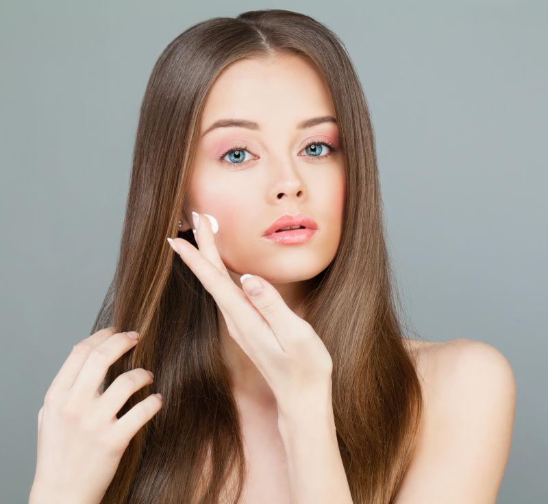 在脸上涂保湿霜的年轻女子SPA模特