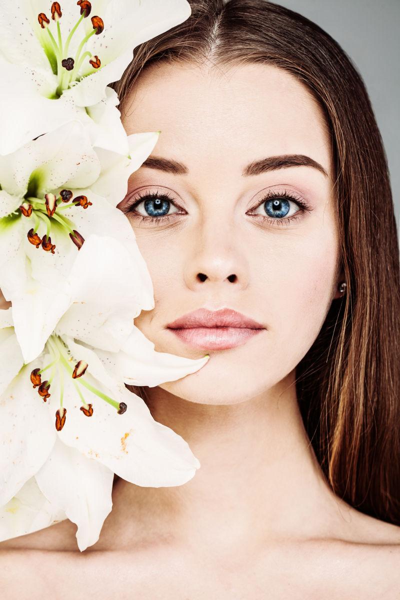 拥有自然妆容的长发美女和脸旁的漂亮的花