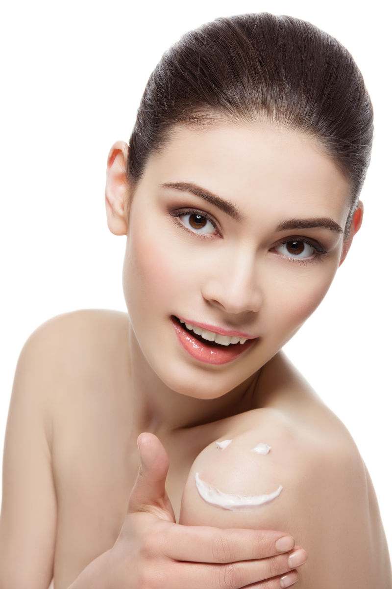 年轻漂亮的女人肩上涂着奶油笑脸