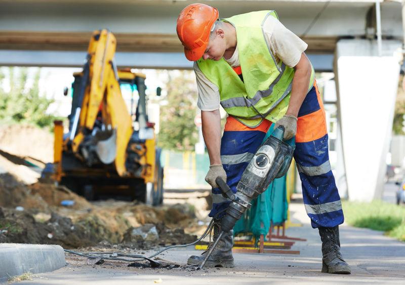 街道上在使用气动锤钻地施工的男人