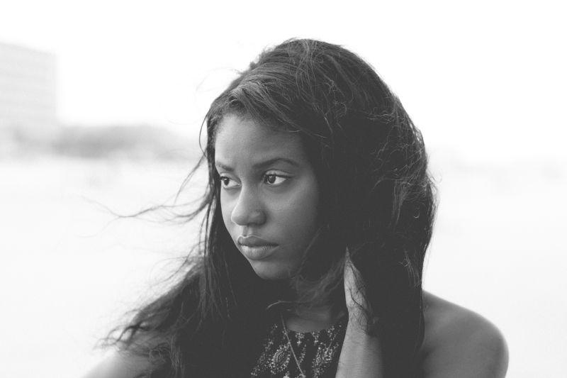 白色背景下的抚摸被头发盖住的耳朵的美女