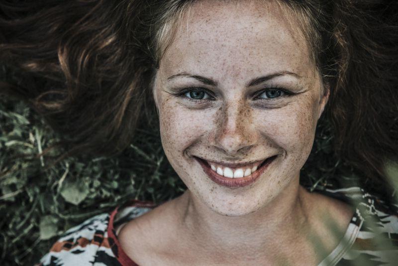 黑色背景上脸上有雀斑的微笑着的美女