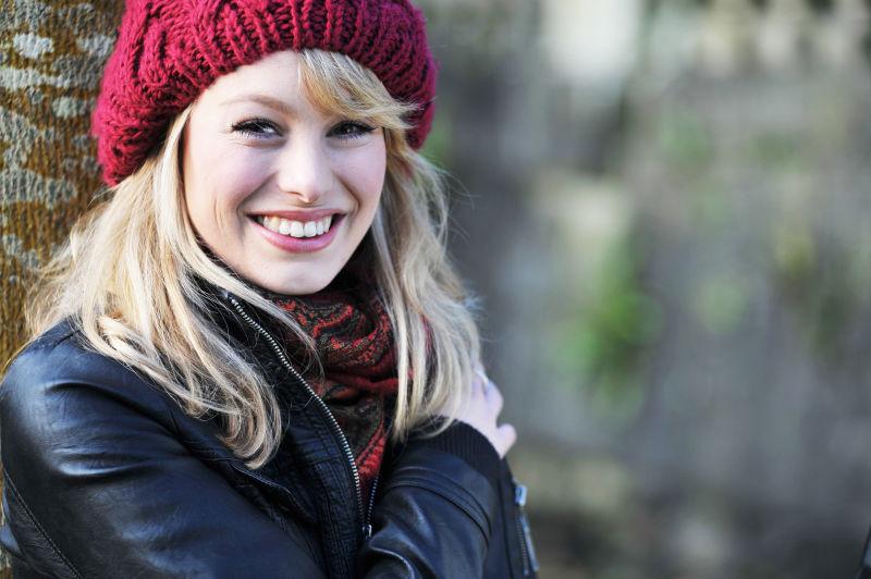 靠着树的年轻的穿着皮衣的高加索女人