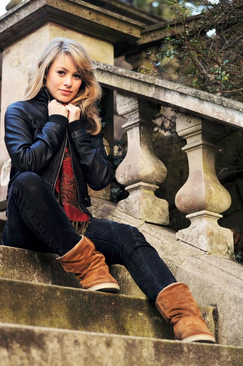 在户外坐在台阶上的穿着皮衣的年轻的金发美女