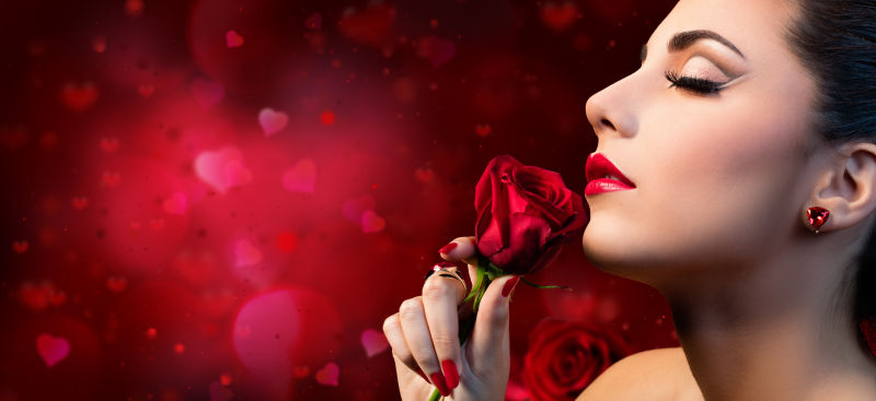 爱心背景前闻着玫瑰的美女