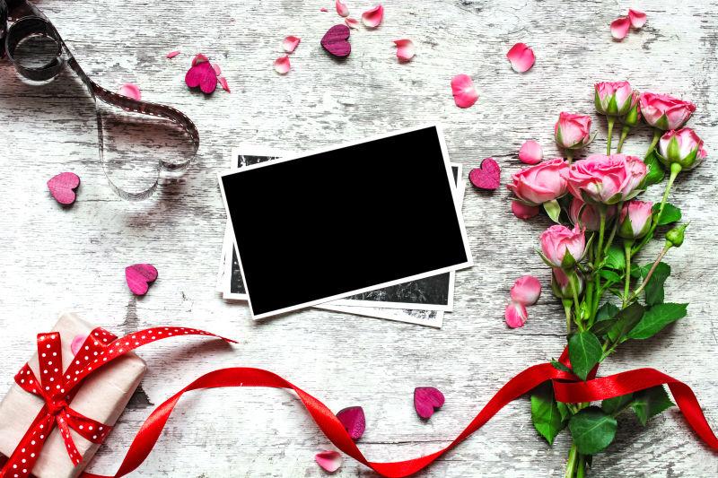 白色桌上玫瑰花束旁的空白相片和黑色底片