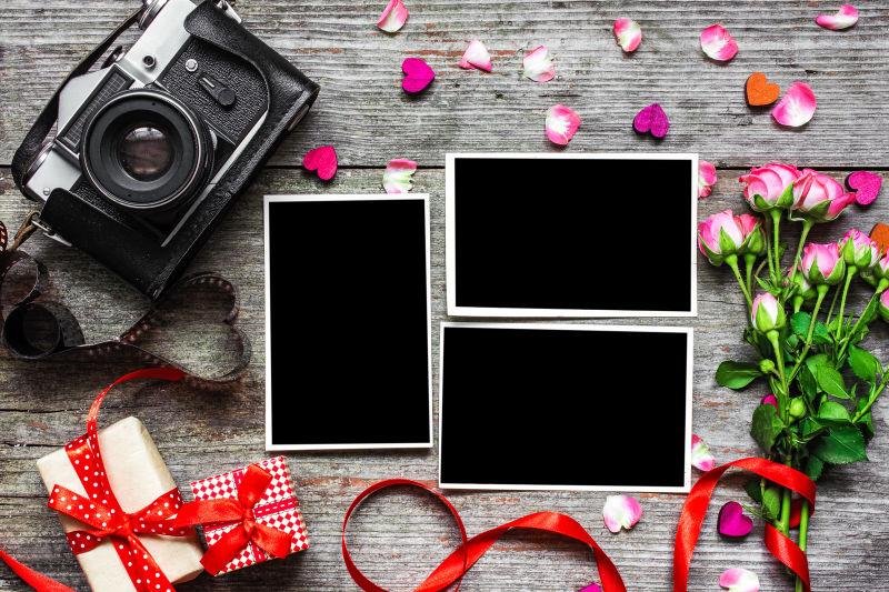 木纹理桌上玫瑰花束旁的复古相机与空白相框
