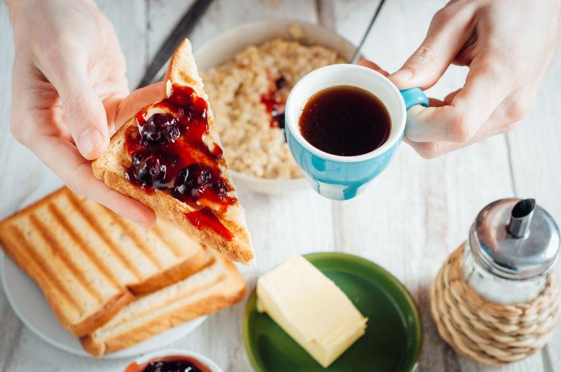 男士吃咖啡和烤面包加黄油和果酱当早餐