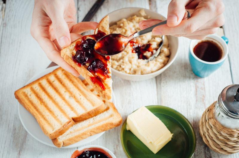 男士吃咖啡和加黄油和果酱的烤面包当早餐