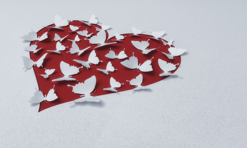大量的白色蝴蝶卡片在红色爱心上