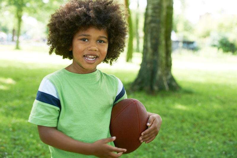 快乐的小男孩在公园玩橄榄球
