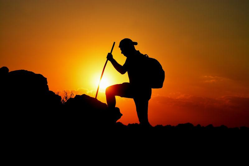 夕阳下向着山顶攀登的登山爱好者