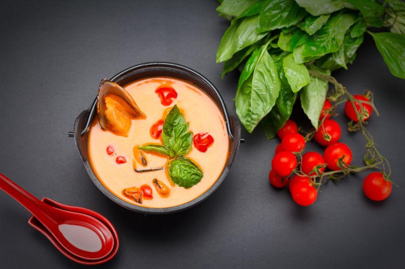 灰色桌上的美味贻贝汤和西红柿等蔬菜