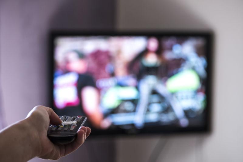 男人拿着遥控对准了电视